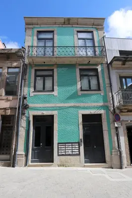 a green building with black doors on a street at HM - Porto Blue Pool Apartment in Porto