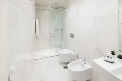 a white bathroom with a shower and a toilet and a sink at bnapartments Cedofeita in Porto