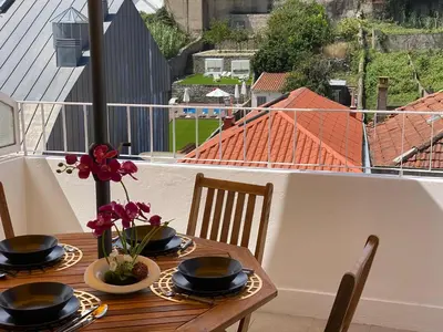 a wooden table with plates and flowers on a balcony at Apartamento com patio na rua principal da cidade in Porto