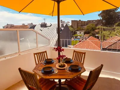 a table with chairs and an umbrella on a balcony at Apartamento com patio na rua principal da cidade in Porto