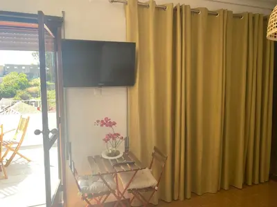 a room with a table and a flat screen tv at Apartamento com patio na rua principal da cidade in Porto