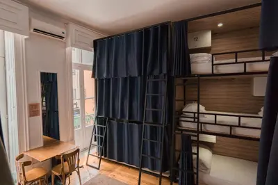 a room with bunk beds and a table and a desk at Rosalma Hostel in Porto