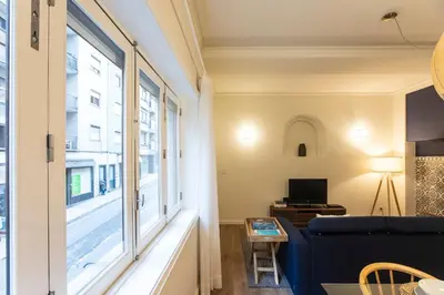 a living room with a blue couch and a window at Tasteful 2BR Flat in Art District by LovelyStay in Porto