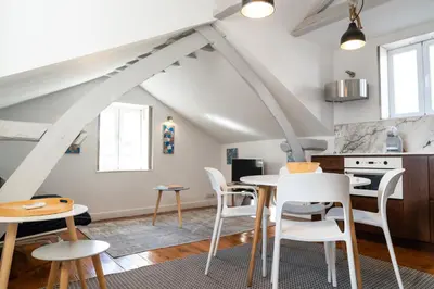 a kitchen and dining room with white chairs and a table at Ribeira Loft in Porto