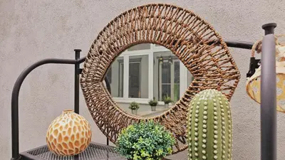 a wicker chair with a mirror on a table at Flores'Old Town - Elegant studio with roomy patio in Porto
