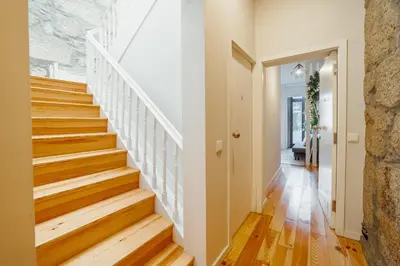 a staircase in a home with wood floors and a stone wall at Apartamento Luminoso no Centro in Porto