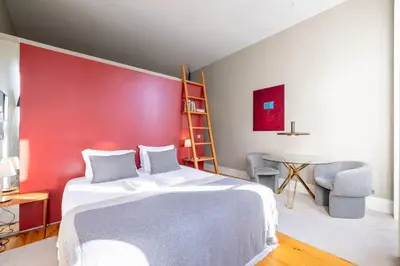a bedroom with a white bed and a red wall at Casa do Ofício - Livreiro in Porto