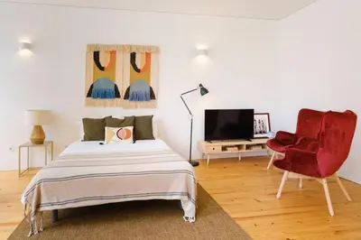 a bedroom with a bed and a red chair at InBloom Apartments 2 in Porto