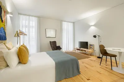 a bedroom with a white bed and a desk and a computer at InBloom Apartments 3 in Porto