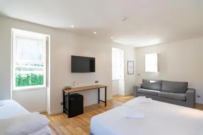 a room with two beds and a couch and a television at The Central House Porto Ribeira in Porto