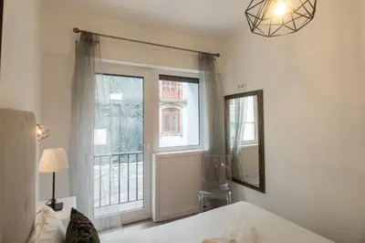 a bedroom with a bed and a large window at Almada Studios & Suites in Porto