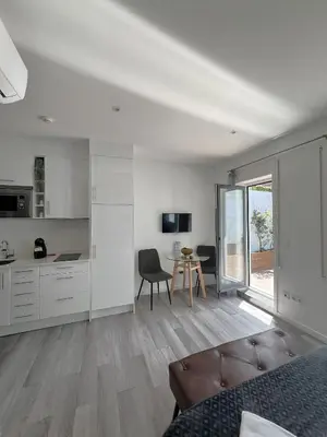 a white room with a kitchen and a table at Almada Studios & Suites in Porto