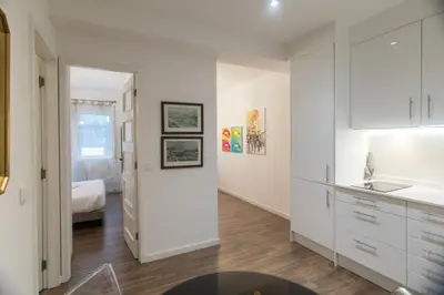 a kitchen with white cabinets and a bed in a room at Almada Studios & Suites in Porto