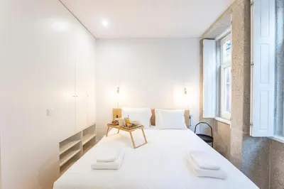 a bedroom with a large white bed and a table at Trendy Vintage Downtown by LovelyStay in Porto