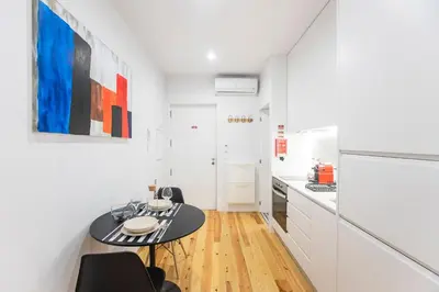 a kitchen with white cabinets and a black table at Trendy Vintage Downtown by LovelyStay in Porto