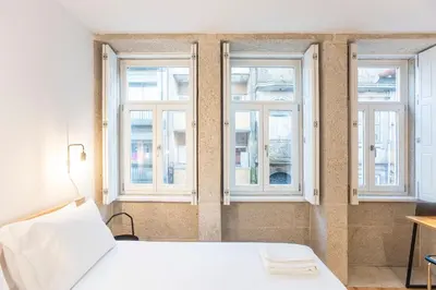 a bed in a room with three windows at Trendy Vintage Downtown by LovelyStay in Porto