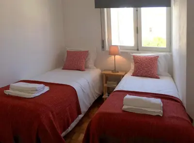 a bedroom with two beds with red sheets and a window at PinPorto City Center III in Porto