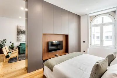 a bedroom with a bed and a flat screen tv at Conceição Premium Downtown Apartment by DA'HOME in Porto