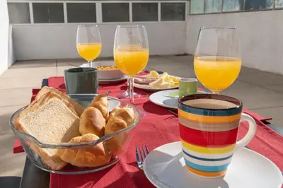 a table with a plate of bread and glasses of orange juice at PortoVivo Quental Terrace in Porto