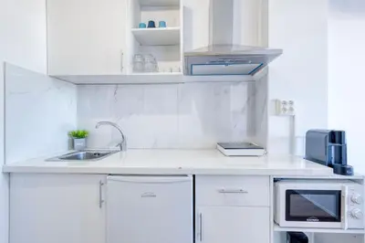 a white kitchen with a sink and a microwave at Travel & Live Bolhão apartments in Porto