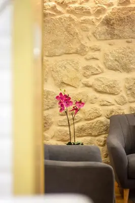 a vase with pink flowers in front of a stone wall at Riverside 2 Bedroom Apartment by DA'HOME in Porto