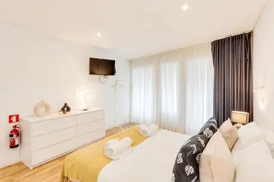 a white bedroom with a white bed and a tv at Bonjardim Downtown Apartments by DA'HOME in Porto