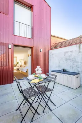 a patio with a table and chairs and a red building at Riva House in Porto