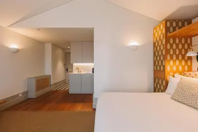 a bedroom with a white bed and a kitchen at Torel Saboaria in Porto
