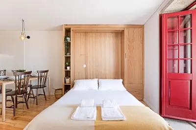 a bedroom with a bed with a red door and a table at Downtown Studio w/ Gorgeous Views by LovelyStay in Porto