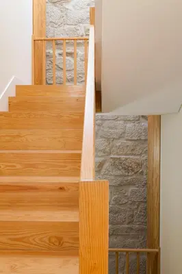 a wooden staircase in a house with a stone wall at VIVA Three Magi Residence in Porto