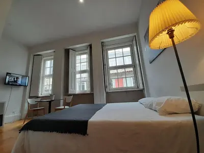 a bedroom with a bed with a lamp and a desk at Great&Cosy São Bento in Porto