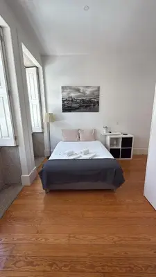 a white bedroom with a bed and two windows at Great&Cosy São Bento in Porto