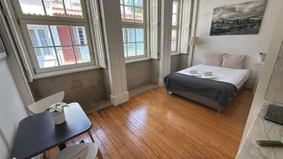 a small room with a bed and a desk and windows at Great&Cosy São Bento in Porto