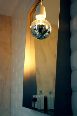 a bathroom mirror with a light and some bottles on a shelf at Villa Invicta II in Porto