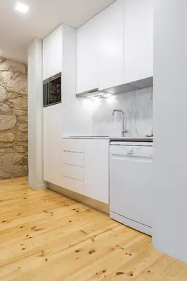 a kitchen with white cabinets and a wooden floor at ORM Carregal Apartment in Porto