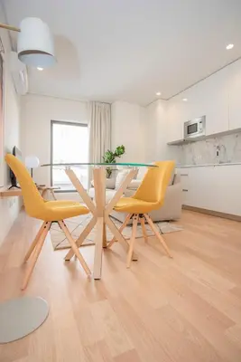 a dining room with a glass table and yellow chairs at Liiiving in Porto - City Design Apartments in Porto