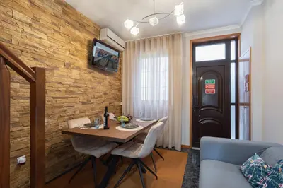 a dining room with a wooden table and a brick wall at Host Wise - Lovely & Cozy House - Prime Location in Vila Nova de Gaia