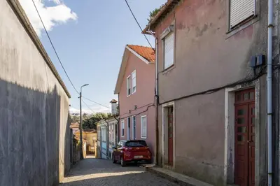 a red car parked in an alley with buildings at Host Wise - Lovely & Cozy House - Prime Location in Vila Nova de Gaia