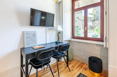 a desk with two chairs and a television on a wall at Josephine Apartments in Porto