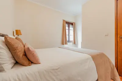 a bedroom with a white bed with pillows and a window at Ribeira Cozy Apartment in Porto