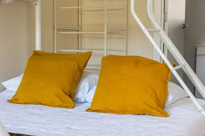 a bed with two yellow pillows and a ladder at House on a rustic Island At Campanha Trainstation in Porto