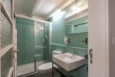 a green tiled bathroom with a sink and a toilet at Duque Oporto Apartment in Porto