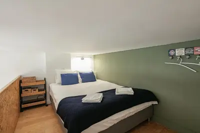 a small bedroom with a bed with blue pillows at Duque Oporto Apartment in Porto