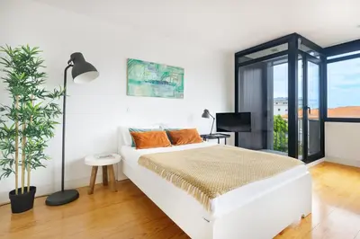 a white bedroom with a white bed with orange pillows at B Porto Casa da Música in Porto