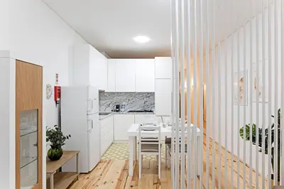 a white kitchen with a white table and chairs at Lóios 1BR Flat Downtown by LovelyStay in Porto