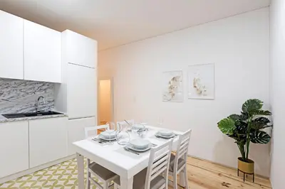 a white dining room with a white table and chairs at Lóios 1BR Flat Downtown by LovelyStay in Porto
