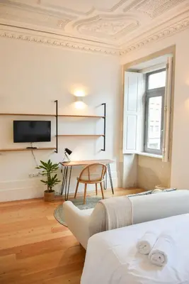 a living room with two beds and a table and a tv at Lindo, funcional e charmoso espaço - Porto - APT H in Porto