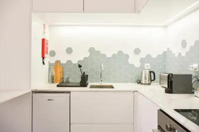 a kitchen with white cabinets and gray hexagonal wall at Lindo, funcional e charmoso espaço - Porto - APT H in Porto