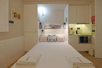 a large white bed in a room with a kitchen at FLH Porto Ribeira Typical Studio in Porto