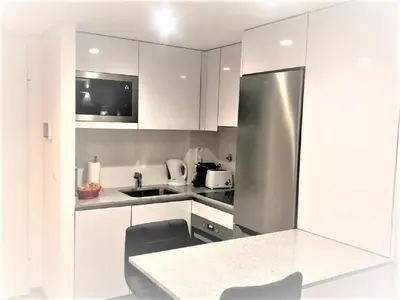 a kitchen with white cabinets and a stainless steel refrigerator at Oporto Yellow Apartments in Porto